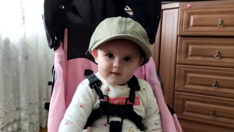 A_Cute_Baby_Named_Zlata_is_Trying_on_Her_Grandfather's_Baseball_Cap