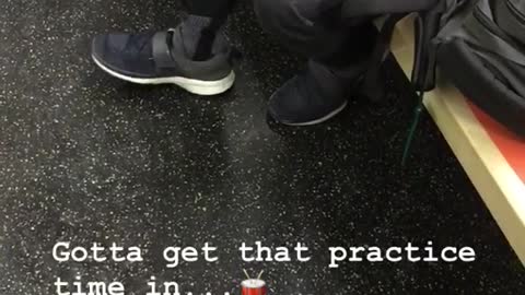 Guy practices the drums with drum pad on lap on subway