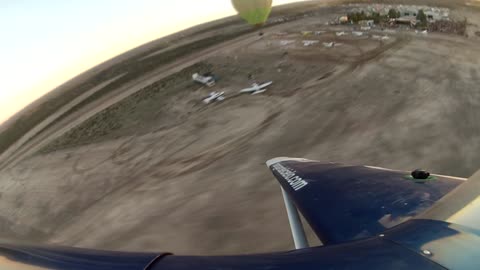 Stunt planes surround hot air balloon during takeoff