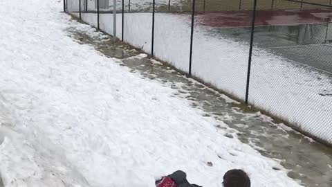 Boy in red beanie backflip fail down snow hill