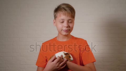 Young boy holding his cute rodent domestic animal in hands.