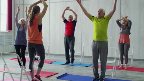 A Woman Fitness Instructor Teaching The Group Of Elderly People Some Exercises Fitted For Them