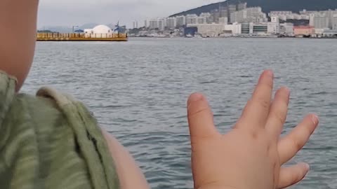 Baby waving to the sea and saying hello.