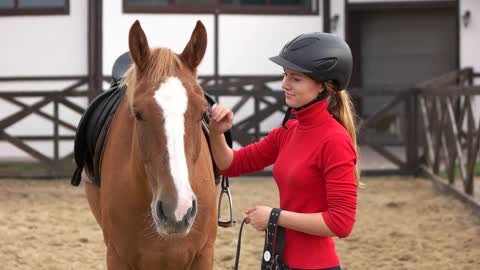 oung woman jockey petting a horse at horse farm