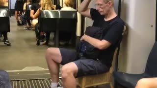 Man black shirt brings own wooden chair on subway