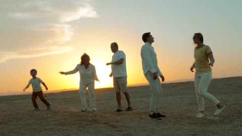 Family dancing at the beach during sunset