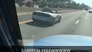 Red surfboard in silver car on freeway