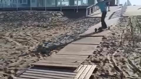 Guy longboard skateboard down wood pier sand falls over