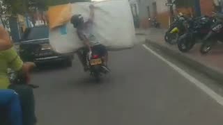 Motociclista transporta colchón en una moto