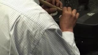 Man plays brown flute in subway