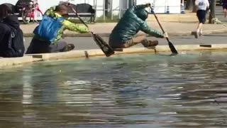 Two guys rowing with paddles in fountain