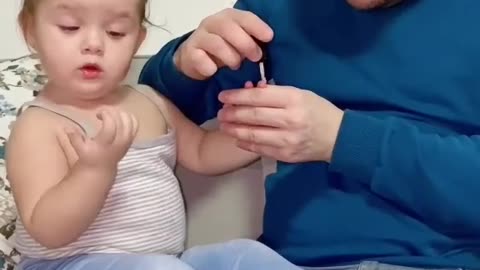Papa is applying nail paint to his daughter