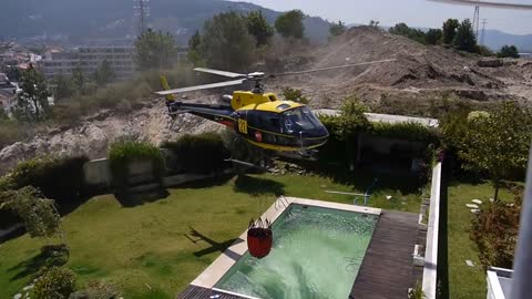 Amazing helicopter pilot taking water from swimming pool