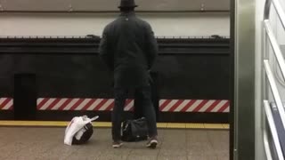 Fedora man does stretches in subway terminal while waiting for 456 train