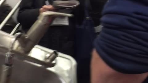 Man has a kitchen sink inside a shopping cart on subway train