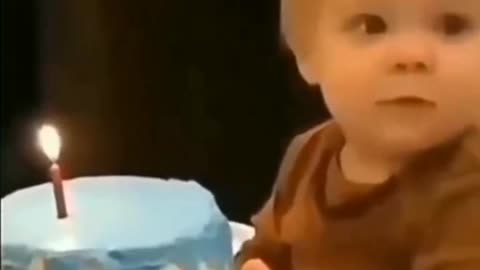 Adorable baby touches lit birthday candle