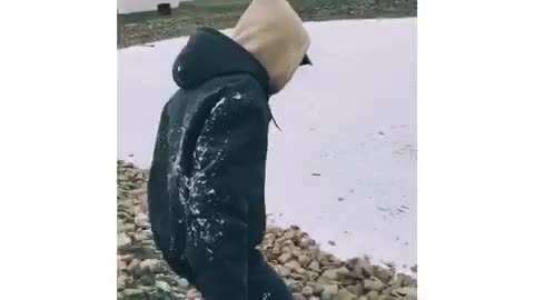 Guy in black jacket with fur slips and slides on frozen lake