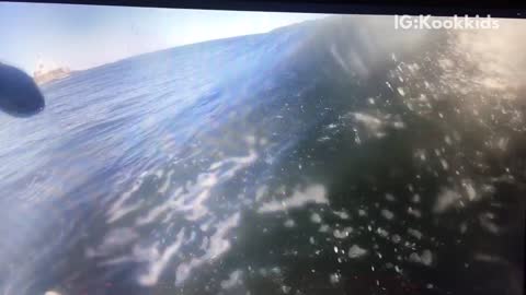 Surfer in black wetsuit falls off surfboard and into water