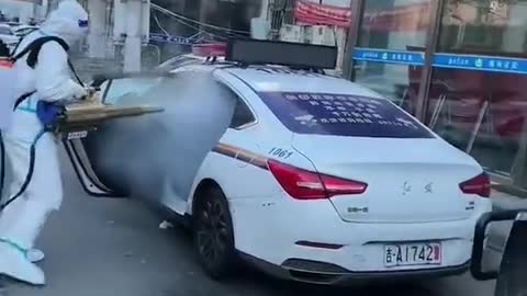 Chinese CCP covid stormtroopers spray a police car