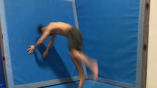 Guy does front flip on gym safety mat and falls
