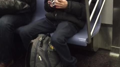 Guy solving white rubik's cube and singing on subway train