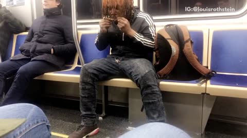 Man in track sweater rolls blunt on subway