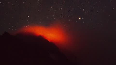 Active volcano smoking during the starry night