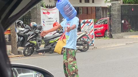 Man Directing Traffic Wears Water Jug in Indonesia