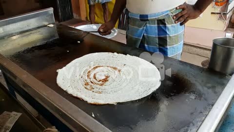 A man making dosa on a huge stone plate