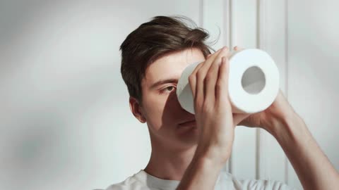 A Man Playfully Using Toilet Papers Foe A Telescope