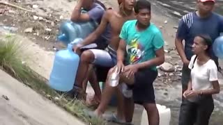Venezuelans collecting water from drainage pipes