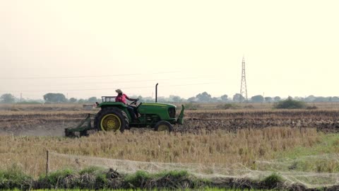 A Farmer Using A Tractor Plow Preparing The Farm Land For Seed Planting