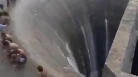 Watch as group of kids stand inches before a dam drain in Águas Vermelhas,