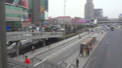 Beijing, China -- People walking to and fro on overpass to major road