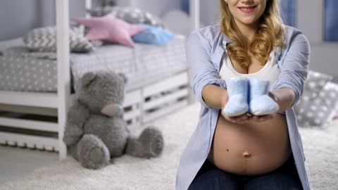 Pregnant woman holding baby shoes