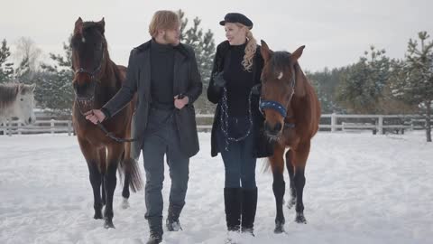 Couple walking with horses outdoors on a country ranch in the winter