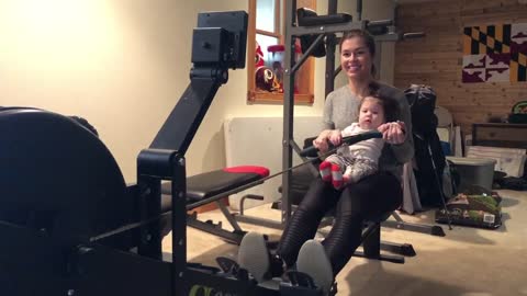 Baby girl and mom workout together on rowing machine