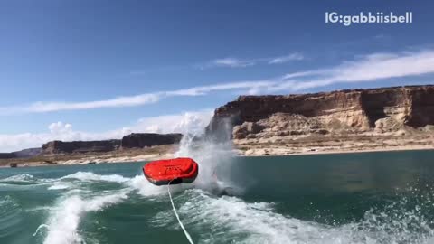 Slow motion three people fall off of red black raft lake