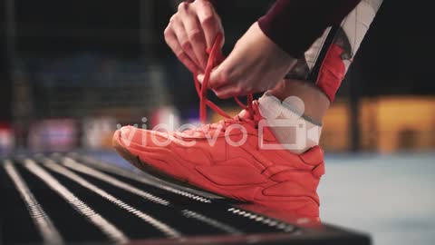 Close Up Of Sportswoman Tying Her Shoelaces On The Bench During Her Training Session At Park At Nigh