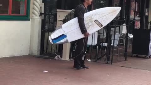 A man carrying a surfboard in a black wet suit