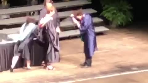 Guy walking across graduation stage trips and falls