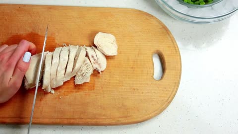 Hands woman cuts boiled chicken with knife on a wooden board food