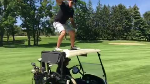 Guy in black shirt on top of golf cart drinking beer falls down