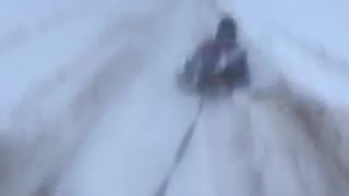 Guy sledding on a frozen beach tied to a car