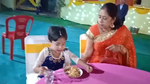Sweet little girl eating noodles with her mother