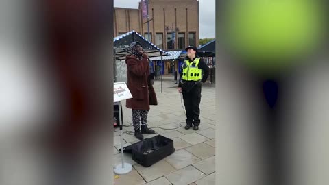 Moment shy policewoman joins busker during street performance