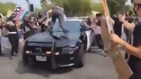 Protesters jump on front of police car and find out