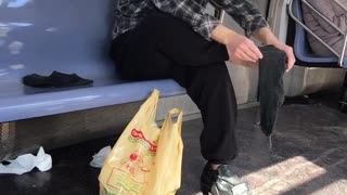 Man rubs bare foot on subway train