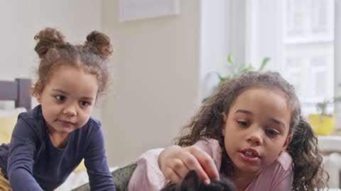 kids petting their cat on the bed.so cute