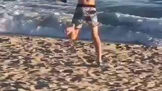 Guy blue shorts running funny on beach toward water